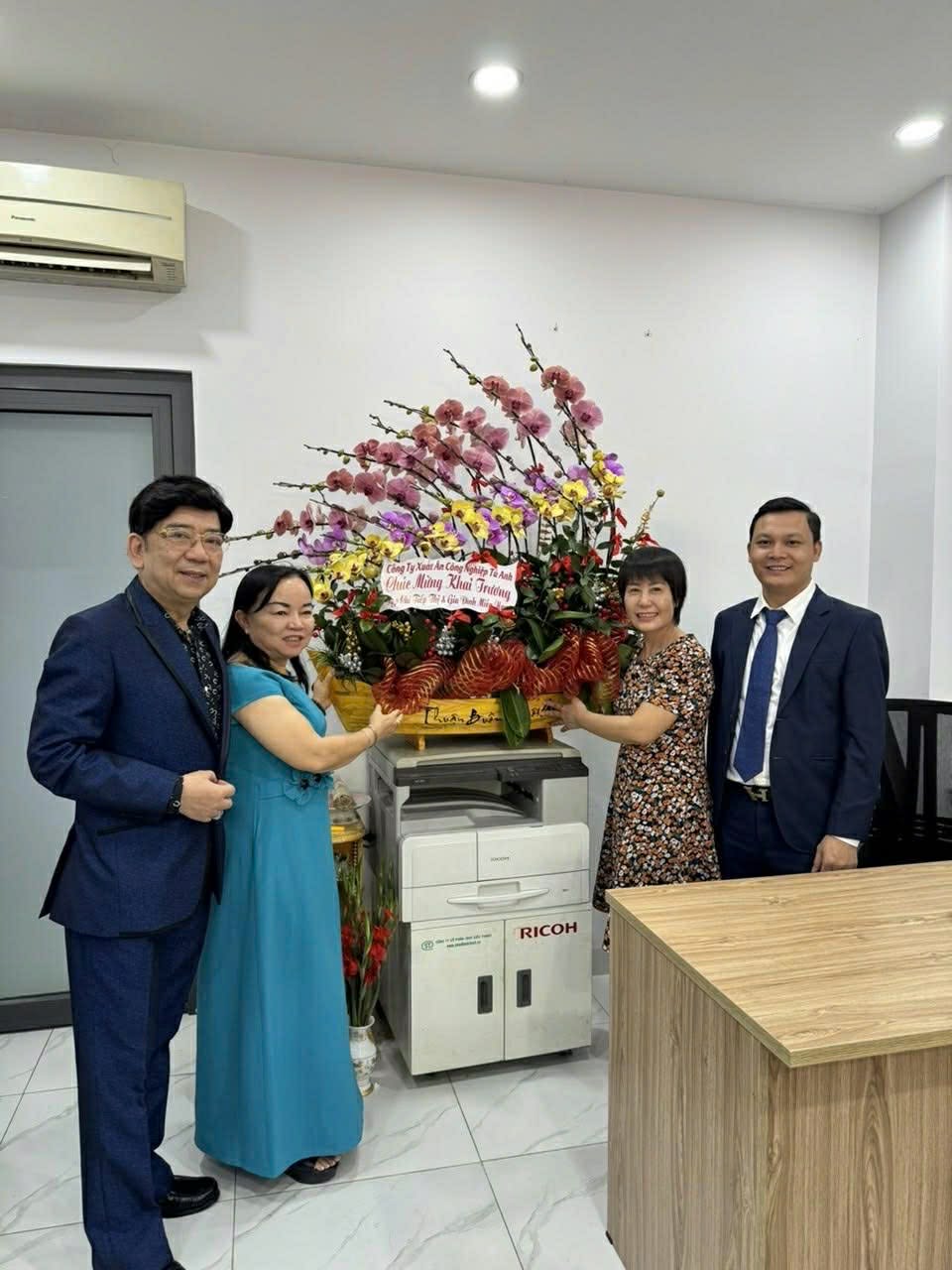 Luật sư Bình Minh chụp ảnh cùng doanh nghiệp và lẵng hoa chúc mừng